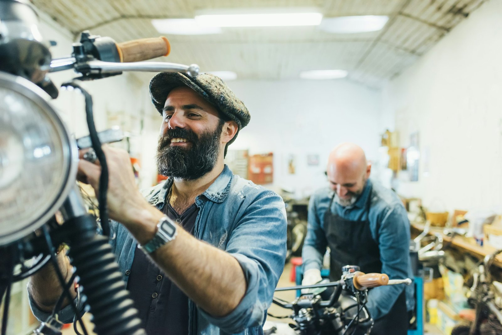 Two mature men, working on motorcycle in garage